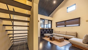 A modern interior with a staircase, a sofa set, and a small table. - 1688 House Churaumi (Motobu)