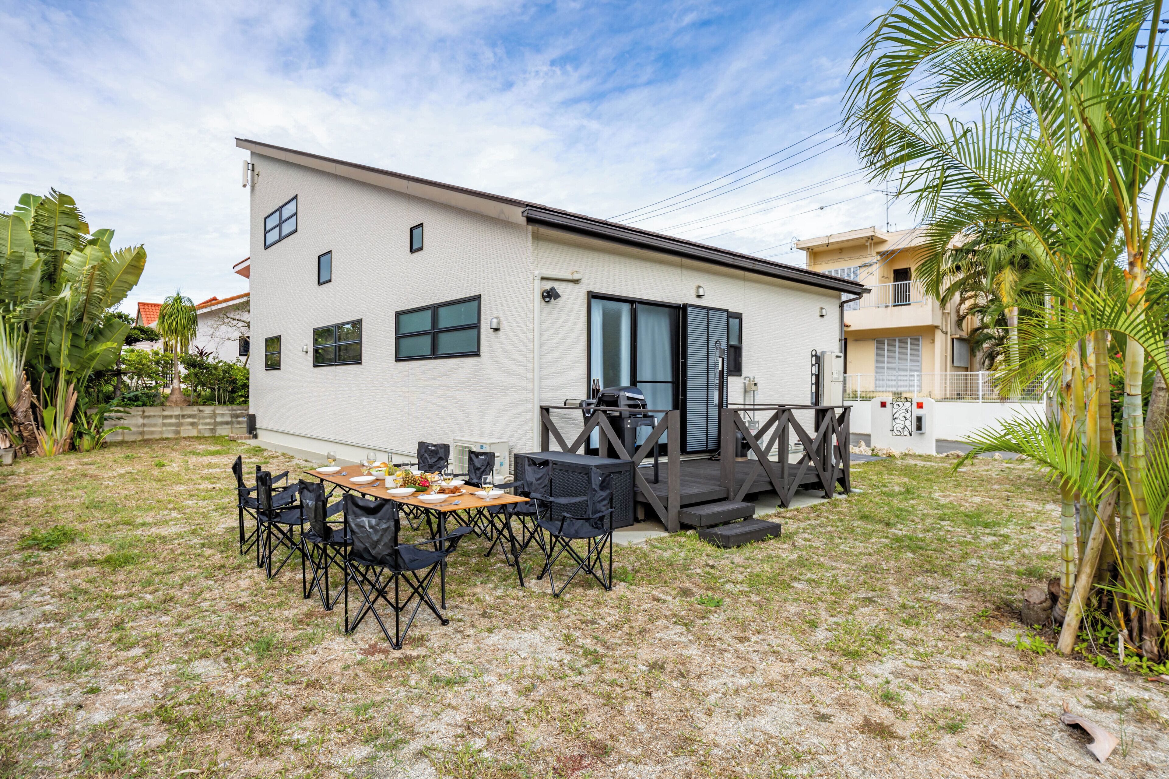 A modern house with a patio area featuring a table and chairs.