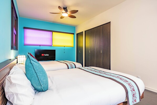 A hotel room with a bed, a ceiling fan, a TV, and a wardrobe. - 1688 House Churaumi (Motobu)
