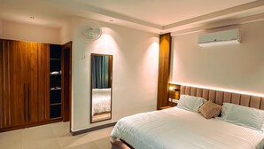 Une chambre à coucher moderne avec un grand lit, une armoire, un miroir et un luminaire fixé au plafond.