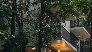 Un immeuble à plusieurs étages doté de terrasses extérieures, de murs en pierre et de luminaires suspendus.