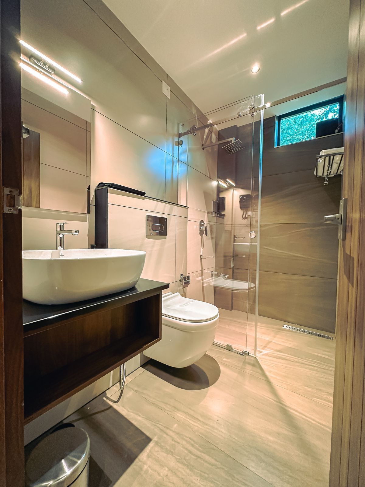 Un baño moderno con un lavamanos grande tipo cuenca, un inodoro y una zona de ducha con mampara de vidrio.