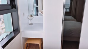 A hotel room with a large window, a small wooden stool, a round mirror, and a bed with a curtain. - The First Ocean Songjung (Busan)