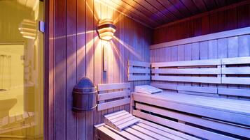Una sauna con bancos de madera y un accesorio de luz en la pared.