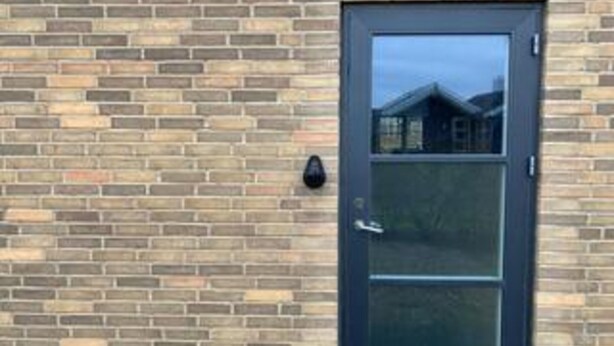 A brick wall with a dark-colored door and a small black object on the wall. - 4 Star Holiday Home in Tarm (Tarm)