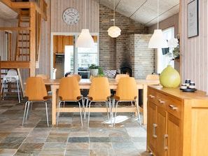 A dining area with a brick fireplace, wooden chairs, and a clock on the wall. - 4 Star Holiday Home in Tarm (Tarm)