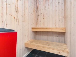 Un sauna con un banco de madera y un armario rojo.