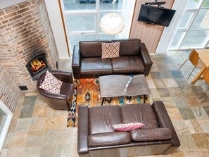 A cozy living room with a fireplace, leather sofas, a coffee table, and a patterned rug. - 4 Star Holiday Home in Tarm (Tarm)