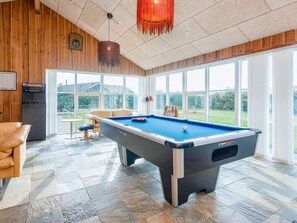 A pool table in a room with large windows, a billiards machine, and a cozy seating area. - 4 Star Holiday Home in Tarm (Tarm)