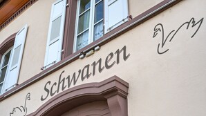 Une façade d’immeuble portant l’inscription « Schwanen » et ornée d’une arche décorative.