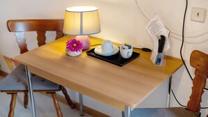 Una mesa de madera con una lámpara, una flor, una bandeja con tetera, una taza y un menú.