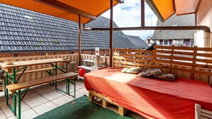 Un espacio al aire libre cubierto con una cama de madera, bancos y una mesa.