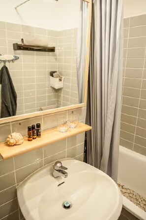 A bathroom with a sink, mirror, shelf with toiletries, and a bathtub. - Apartment 'Ferienwohnung Flensburger Brise' with Balcony and Wi-Fi (Flensburg)