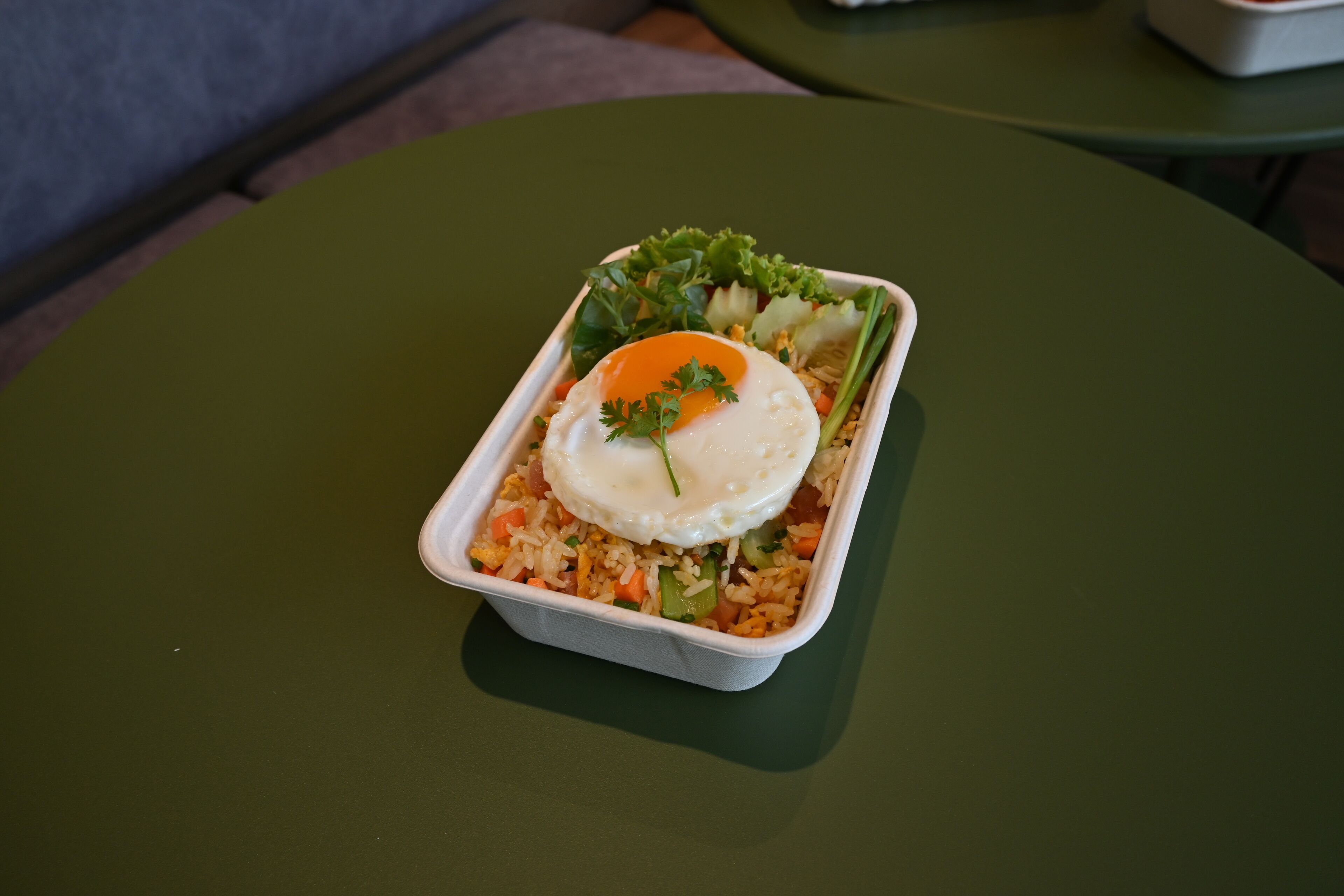 A meal in a takeout container on a green table.