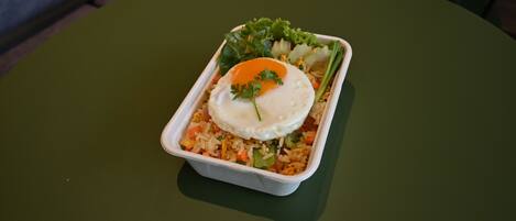 A meal in a takeout container on a green table.