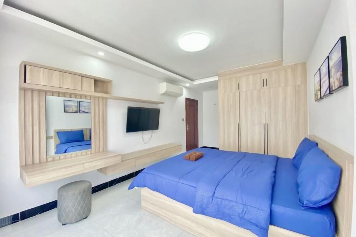 Un dormitorio moderno con una cama grande, armario empotrado y televisor de pantalla plana.