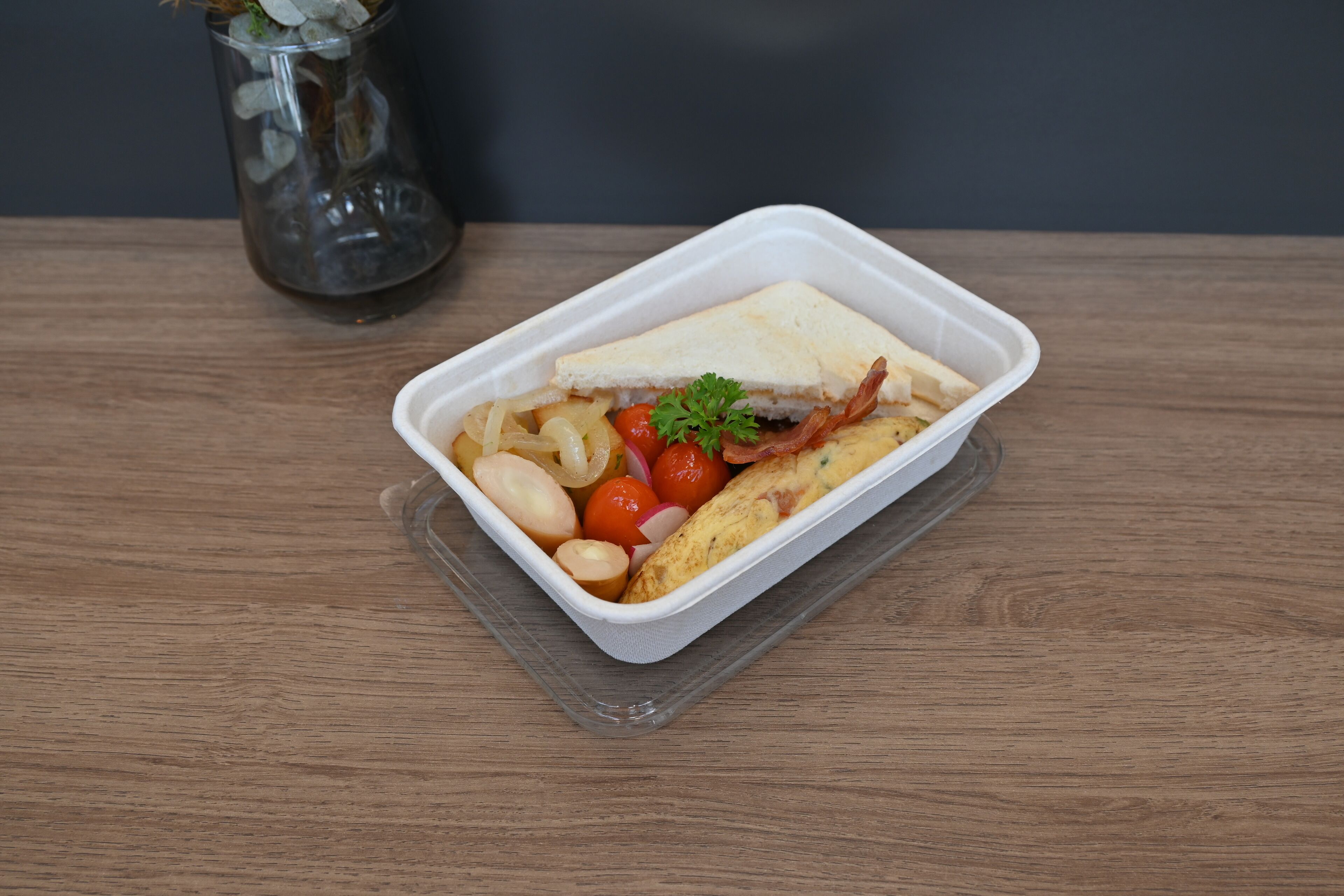 A meal in a clear plastic container on a wooden table.