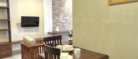 A dining area with a wooden table, chairs, and a TV mounted on the wall.