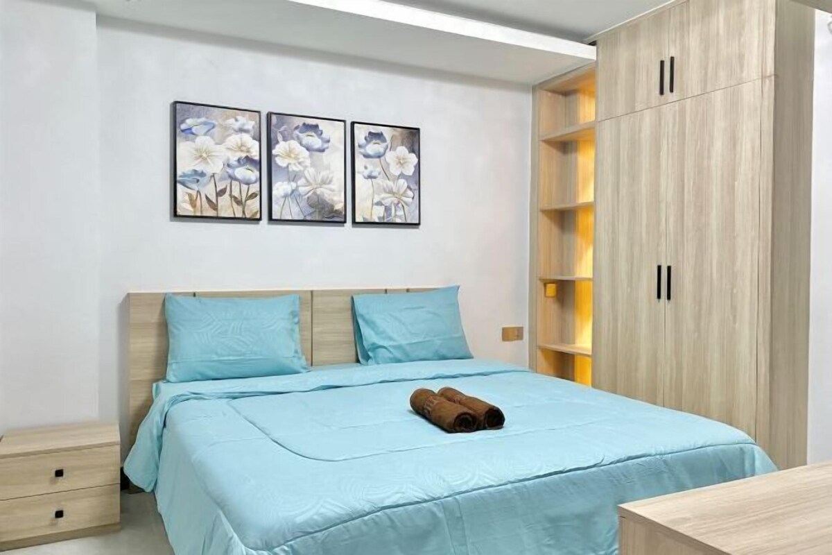 Un dormitorio con una cama, una mesita de noche, un armario y dos cuadros colgados en la pared.