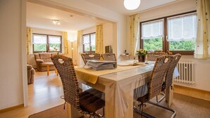 A dining area with a table, chairs, and a view of greenery outside.