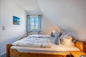 Une chambre à coucher avec un lit en bois, une fenêtre avec des rideaux, une lampe de chevet et un tableau accroché au mur.