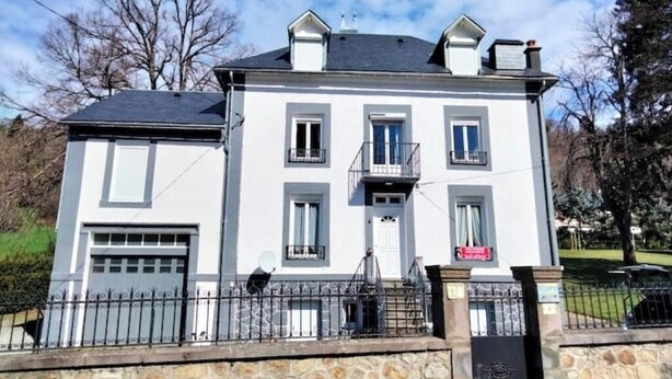 Un bâtiment à deux étages, doté d’une façade blanche, de fondations en pierre et d’une clôture en métal noir.