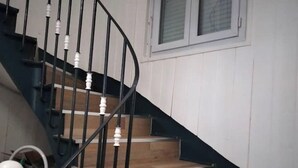 Un escalier avec des rampes noires et des balustrades blanches, menant à un palier doté d’une fenêtre.
