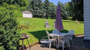 Une terrasse avec une table et des chaises, un barbecue et un parasol.
