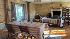 A cozy room with a dining table, chairs, a bed, a fireplace, and a bookshelf. - Charming Périgord farmhouse with breathtaking views over the valley and garden (Issac)