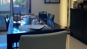 Un comedor con una mesa de vidrio, sillas y un cuadro en la pared.