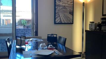 Zona pranzo con tavolo in vetro, sedie e un quadro appeso al muro.