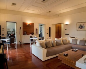 A modern living room with a sofa, coffee table, and dining area. - b&b mimmù (Naples)
