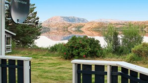Vista panorámica de un lago con montañas al fondo, una valla de madera y una antena parabólica con la etiqueta "Canal Digital".