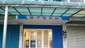 A hotel entrance with a blue shutter door, a glass entrance, and a sign above the door. - Sunmoonstar Hostel (Budai)