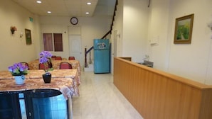 A hotel lobby with a reception desk, a clock on the wall, and a staircase leading to another floor. - Sunmoonstar Hostel (Budai)