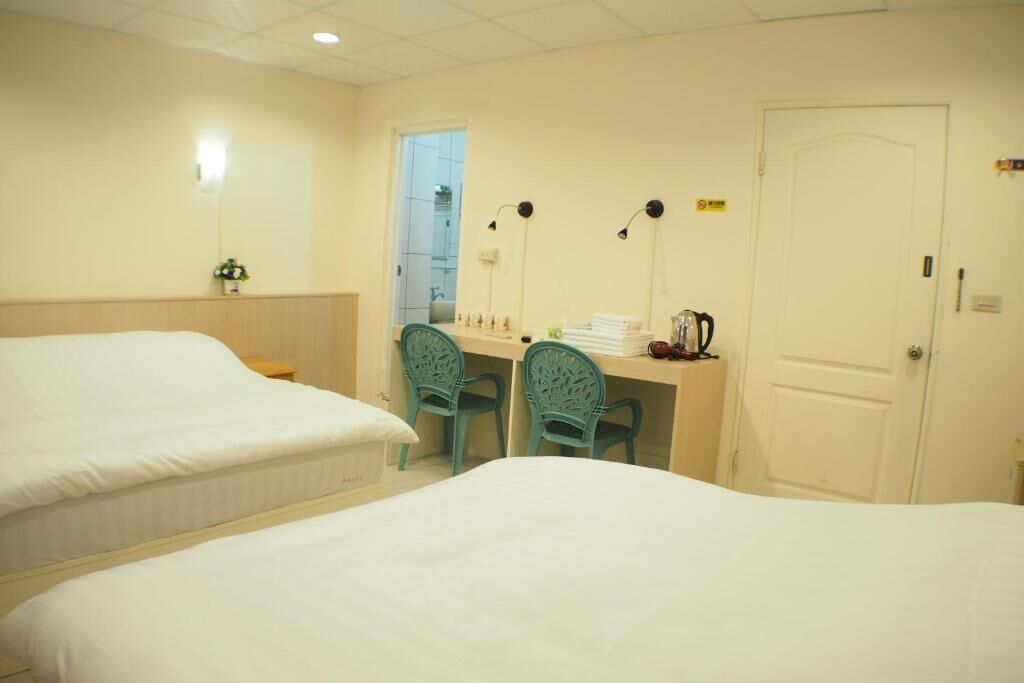 Habitació d'hotel amb dos llits, una taula de treball amb cadires, una porta i una finestra.