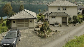 A two-story house with a garage, a small attached shed, and a car parked in front. - 4 Star Holiday Home in Syvde (Vanylven)