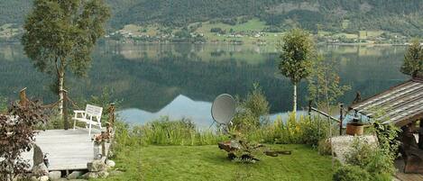A lakeside property with a deck, a satellite dish, and a rustic cabin.
