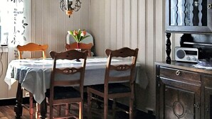 A dining area with a table, chairs, a hanging light fixture, and a radio on a cabinet. - 6 Person Holiday Home in Ovre Ardal (Ardal)