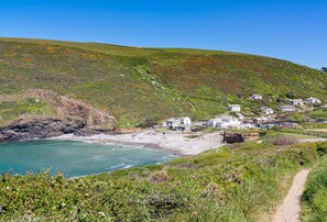 A coastal village with houses on a hillside, a sandy beach, and a clear blue sky. - Dipple Mill Cottage is nestled in 27 acres of serene countryside (Bideford)