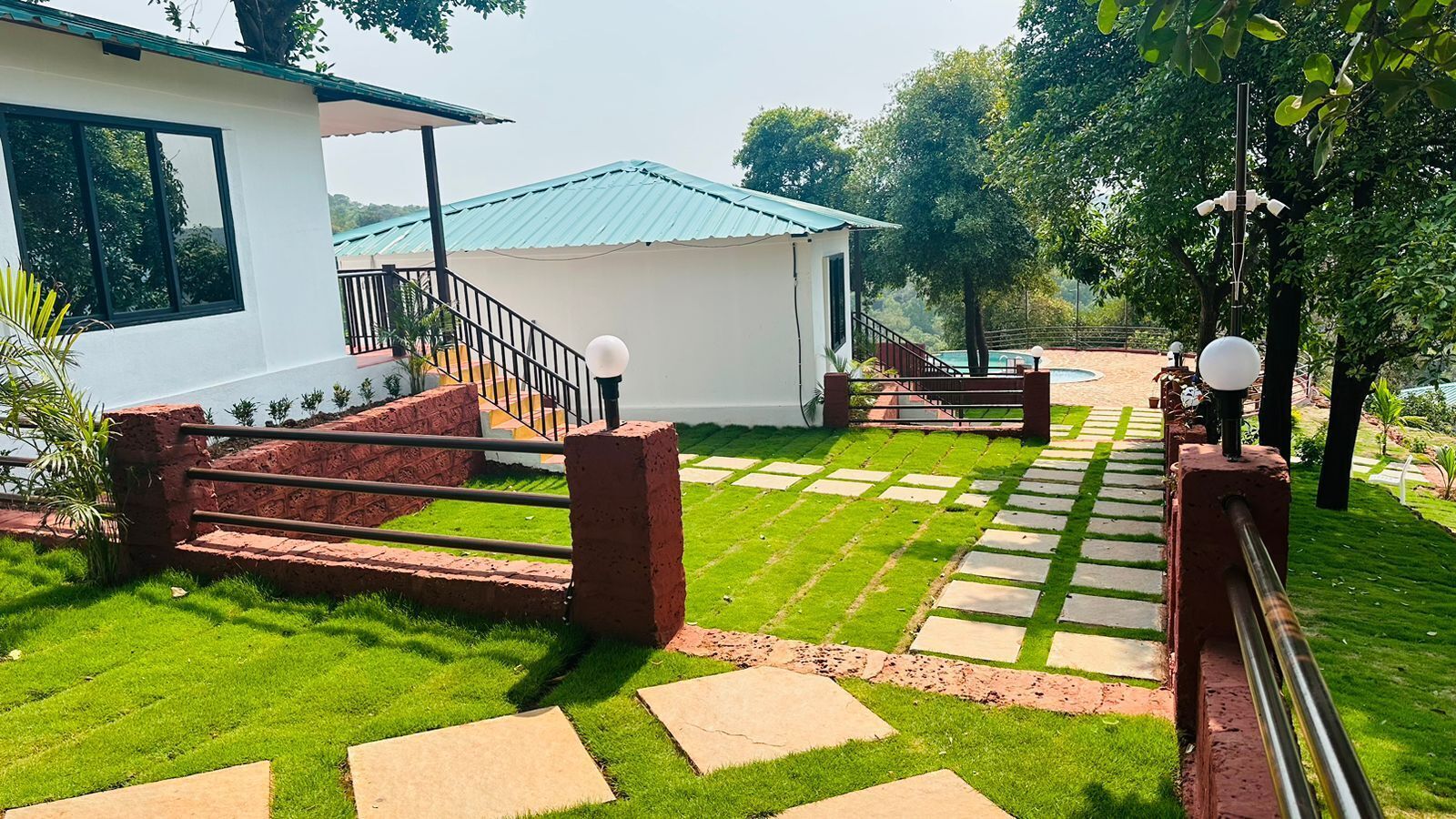 A well-maintained garden with a paved pathway leading to a white building with a blue roof.