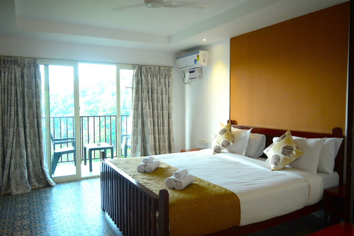 Habitación de hotel con cama, una silla, una mesa y vistas al exterior a través de una puerta corredera.