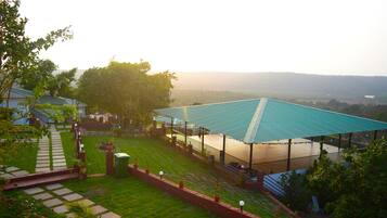 A garden with a paved walkway, a covered seating area, and a view of the surrounding landscape.