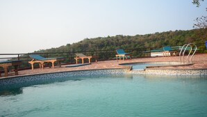 Une piscine avec des chaises longues et un kiosque.
