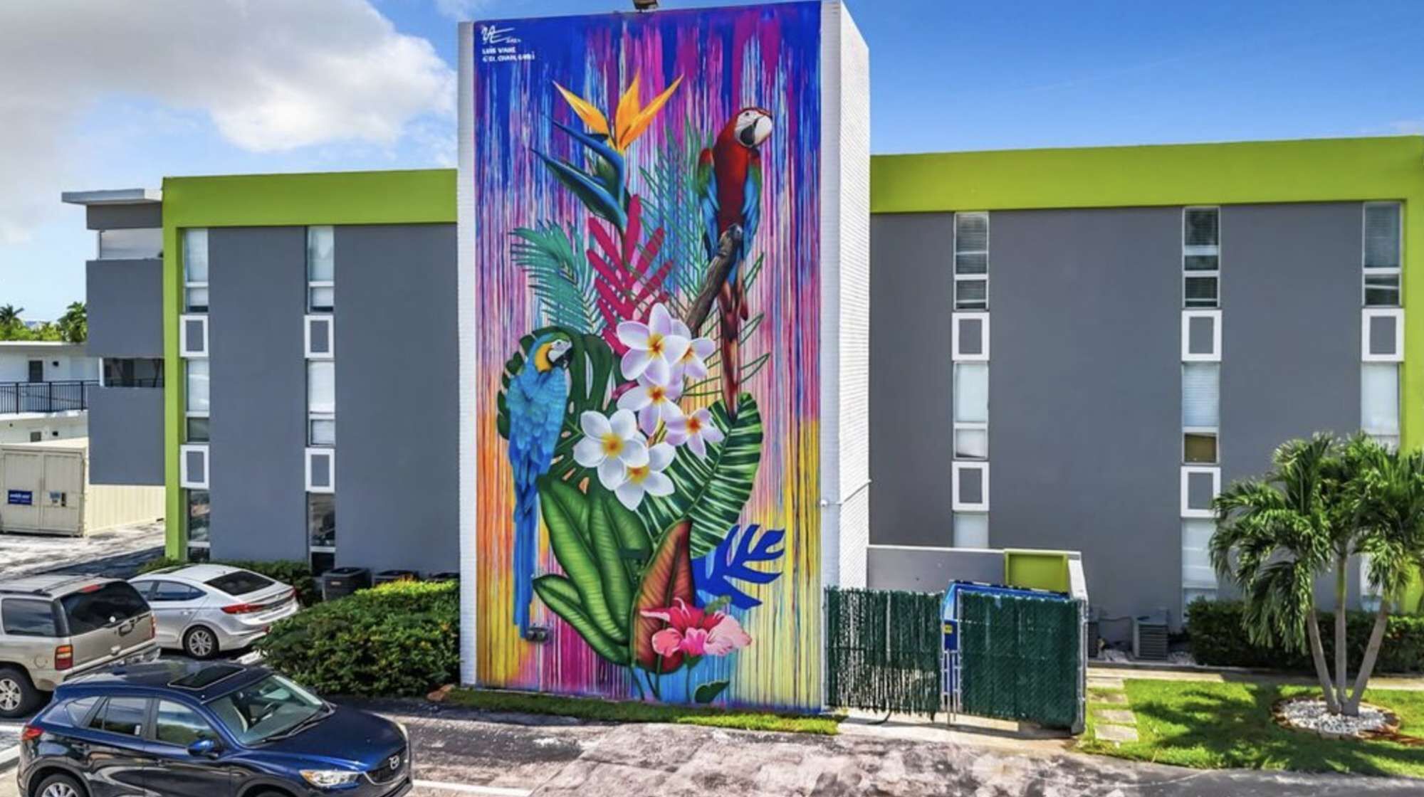 En bygning med et farverigt mural af en papegøje og tropiske blomster.