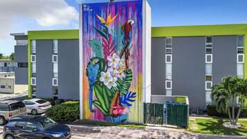 En bygning med et farverigt mural af en papegøje og tropiske blomster.