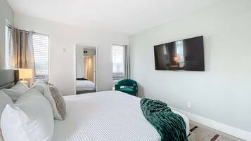 A hotel room with a large bed, a TV mounted on the wall, and a view of the hallway.