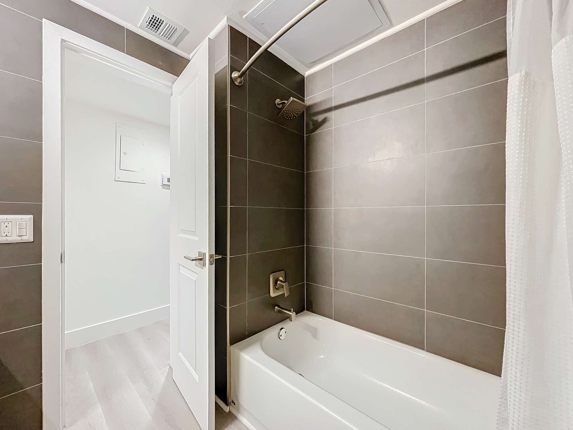 A modern bathroom with a bathtub, a shower area, and a white door.
