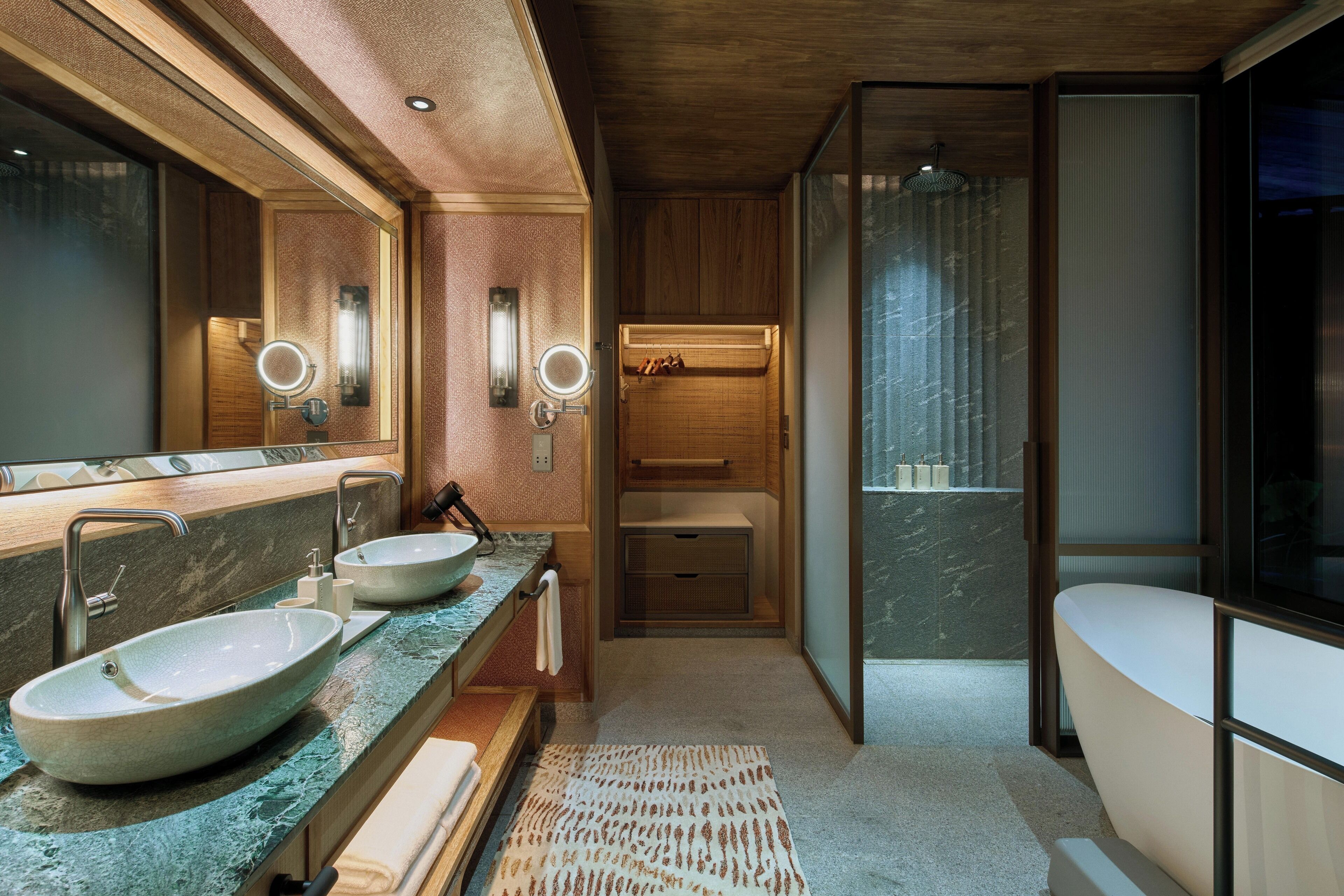 Un baño moderno con dos lavabos, un espejo grande y una bañera.