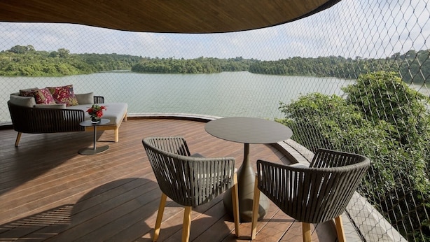 Una terraza con sofá, sillas y una mesa con vistas a un lago.